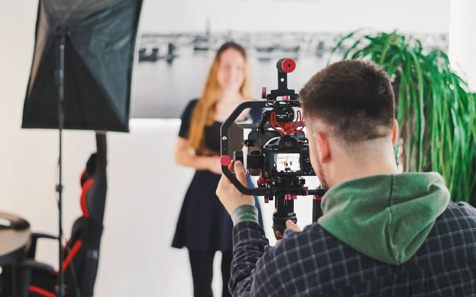 Am Set: Kameramann filmt eine Frau im Studio vor heller Wand